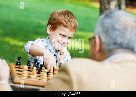 Großvater und Enkel spielen Schach im park Stockfoto