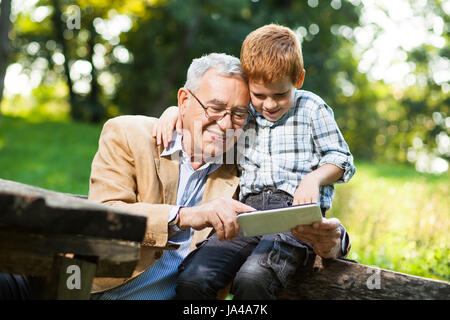 Großvater und Enkel sind digitale Tablet im Park verwenden. Stockfoto