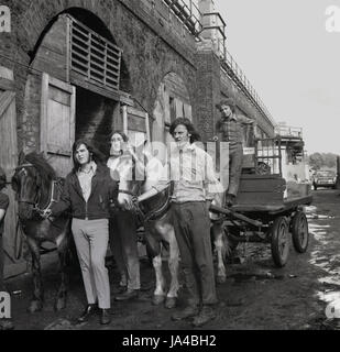 1970er Jahre, Histroical, Bögen Gruppe von jungen, männlichen Erwachsenen wankt, oder Lappen und Knochen Männer mit Pferd und Wagen außerhalb ihrer Depot am alten Bahnhof, Süd-London, England, UK. Stockfoto