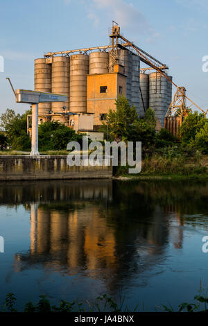 Alte Fabrik mit Silos und Reflexion auf dem Wasser Stockfoto