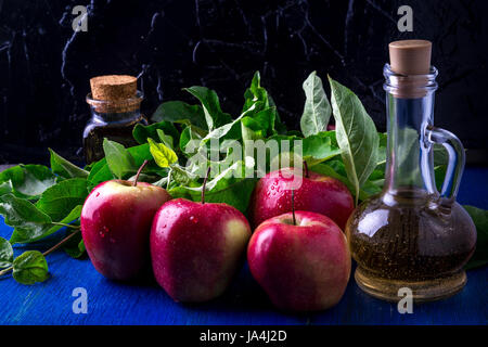 Apple Apfelessig. Drei Glasflasche auf blauem Hintergrund. Rote Äpfel Stockfoto