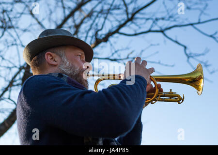 Eine ältere Musiker spielt auf der Straße auf einer Trompete im Frühling Stockfoto