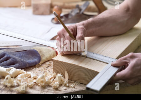 Der Schreiner macht Markierungen mit einem Bleistift auf einer Holzleiste. Vorbereitung für Schreinerarbeiten in der Zeichnung Stockfoto