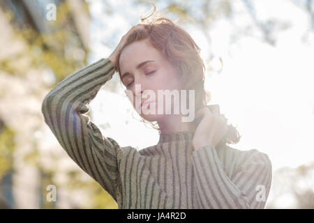 Ein rothaariges Mädchen mit locken im Park steht und schaut leider Weg. Stockfoto