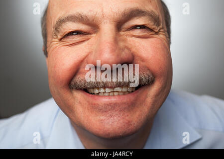 Älterer Mann lacht von Ohr zu Ohr, kichert über die lustigen Geschichten. Gerne von Neuigkeiten oder Veranstaltungen Stockfoto