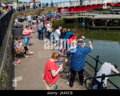 Urlauber im Frühjahr Angeln für Krabben an der Brücke in Whitby Hafen North Yorkshire England UK Stockfoto