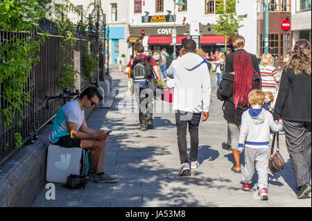 Ein Deliveroo Fast Food Delivery Fahrer nutzt sein Handy auf eine Pause in Cork, Irland. Stockfoto