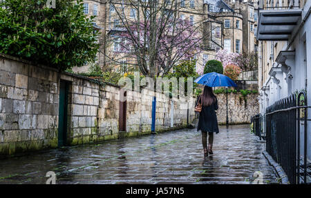 Frau, die entlang einer ruhigen Gasse im Regen Stockfoto