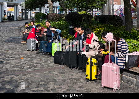 Horizontale Ansicht der Festlandchinesen mit Koffern nach einem Einkaufsbummel in Hong Kong, China. Stockfoto