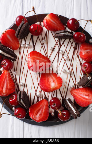 Köstliche Sommer-Torte mit Erdbeeren und Kirschen, dekoriert mit Nahaufnahme Kekse auf dem Tisch. Vertikale Ansicht von oben Stockfoto