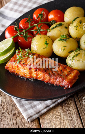 Gegrillter Lachs und neuen Kartoffeln mit Butter und Kräutern Closeup auf einem Teller. Vertikal Stockfoto