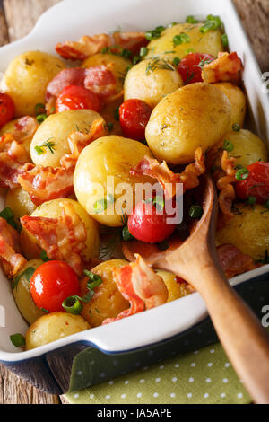 einfaches Essen: neue Kartoffeln gebacken mit Speck und Tomaten in die Auflaufform hautnah. vertikale Stockfoto