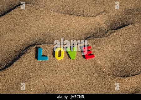 LIEBESWORT mit bunten Buchstaben auf weichem Sand der Wüste Stockfoto