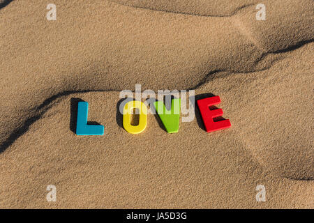 LIEBESWORT mit bunten Buchstaben auf weichem Sand der Wüste Stockfoto