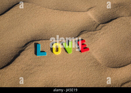 LIEBESWORT mit bunten Buchstaben auf weichem Sand der Wüste Stockfoto