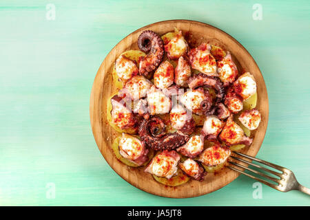 Eine obenliegende Foto von Pulpo a la Gallega, eine Krake mit gekochten Kartoffeln, typische spanische galizische Gericht, auf einer traditionellen hölzernen Platte eine Krickente backg Stockfoto