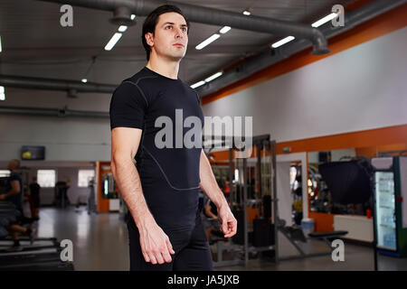 Porträt des jungen schönen Sportler in der schwarzen Sportwear stehend mit im Fitness-Studio Stockfoto