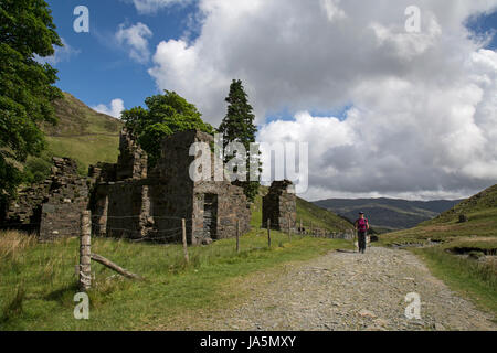 Weibliche Wanderer vorbei an einem verfallenen Gebäude auf Watkin-Weg bis zum Snowdon, der höchste Gipfel in Snowdonia-Nationalpark in Wales. Stockfoto