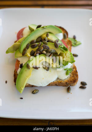 Avocado, Mozzarella-Käse, Tomaten und gerösteten Kürbis Samen auf eine Scheibe Vollkorn toast Stockfoto