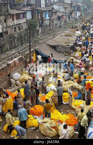 Menschen Sie Kauf und Verkauf von bunten Blumen und Girlanden neben einer Bahnlinie auf dem Blumenmarkt in West Bengal Kolkata Indien. Stockfoto