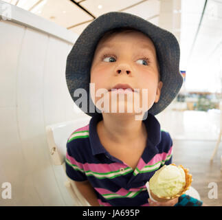 Der kleine Junge isst Eis im Shoping-Zentrum Stockfoto