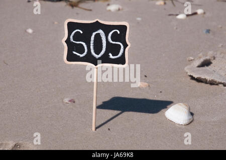 hölzerne Gedenktafel mit einer Inschrift am Strand sos Stockfoto