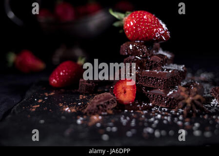 Erdbeer liegend auf einer Pyramide von Schokolade mit anderen Erdbeeren und alte silberne Vase in Scheiben geschnitten Stockfoto