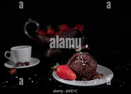 Kaffee mit Muffin auf schwarzem Hintergrund Stockfoto