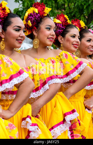 Eine Gruppe mexikanischer Mariachi-Tänzerinnen, die mexikanische traditionelle sinaloa-Kleider tragen, gelbe Kleider tragen, Mexikos kulturelles Erbe feiern, Folkloretanz, Gruppenfoto, Seitenansicht. Stockfoto