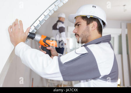 junger Mann Bohren Wand im Innenbereich Stockfoto