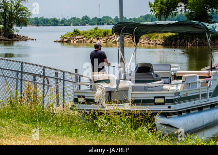 Ein kaukasischer Mann in seinen 40ern Fische aus einem Ponton-Boot auf dem North Canadian River in der Nähe von Oklahoma City, Oklahoma, USA. Stockfoto