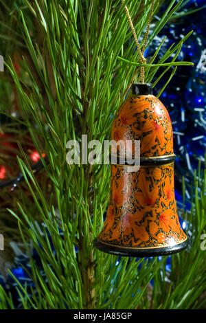 gemalte hölzerne Bell und Lametta am Weihnachtsbaum Stockfoto