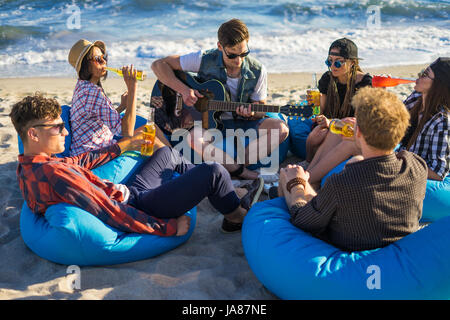 Gruppe von Freunden mit Gitarre und Alkohol auf der Beach-party Stockfoto