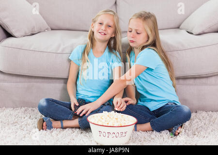 Junge Zwillinge Essen Popcorn sitzt auf einem Teppich im Wohnzimmer Stockfoto