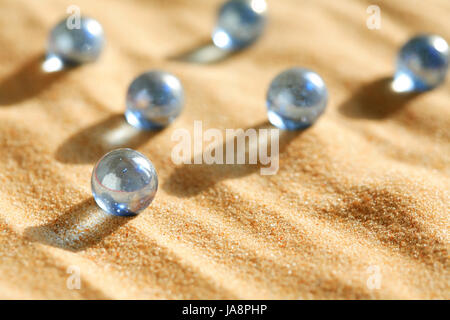 Abstrakte Komposition mit einigen blauen Glaskugeln auf Sandboden Stockfoto