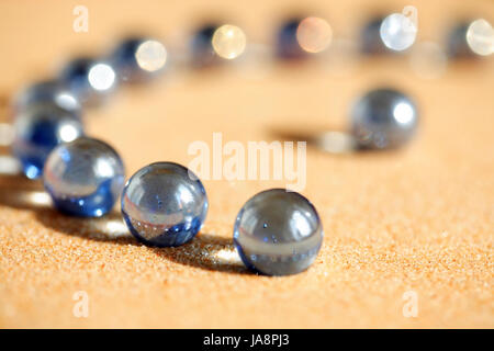 Abstrakte Komposition mit einigen blauen Glaskugeln auf Sandboden Stockfoto