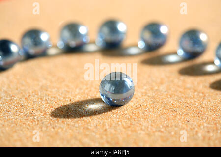 Abstrakte Komposition mit einigen blauen Glaskugeln auf Sandboden Stockfoto