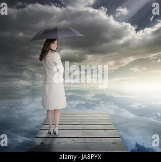 Geschäftsfrau auf der Brücke stehen und halten einen Regenschirm Stockfoto