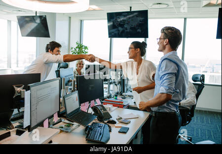 Geschäftskollegen schütteln sich im Büro die Hände. Glückliche Geschäftsleute feiern Erfolg im modernen Büro. Stockfoto