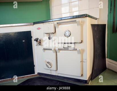 Vintage-cremefarbene Holzofen in einer altmodischen Küche mit grünen Wänden und gefliesten Backsplash, die an Nostalgie und Geschichte erinnern Stockfoto