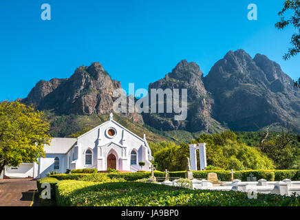 Malerische weisse Holländischen Kap Kirche, Franschhoek, Westkap, Südafrika, mit Bergkulisse und blauer Himmel Stockfoto