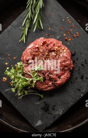 Rohen Boden Rindfleisch Fleisch Steak Schnitzel mit Kräutern und Gewürzen am schwarzen Brett. Restaurant Stockfoto