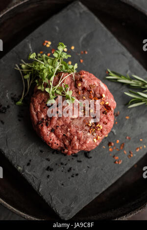 Rohen Boden Rindfleisch Fleisch Steak Schnitzel mit Kräutern und Gewürzen am schwarzen Brett. Restaurant Stockfoto