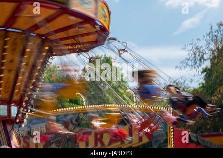 Chain Gang Karussellfahrt auf einem Jahrmarkt mit Bewegungsunschärfe bei Sonnenuntergang Stockfoto
