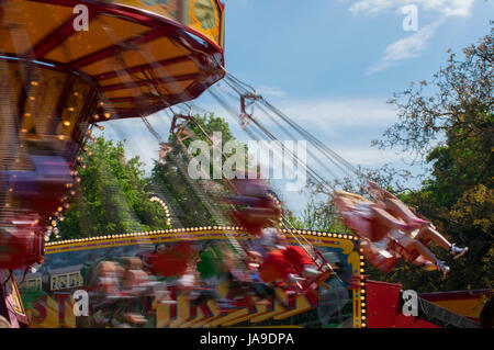 Chain Gang Karussellfahrt auf einem Jahrmarkt mit Bewegungsunschärfe bei Sonnenuntergang Stockfoto