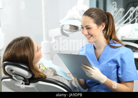 Zahnarzt hält eine Anamnese Fragen, Informationen zu einem Patienten vor der Behandlung sitzt auf einem Stuhl in einer Klinik-box Stockfoto