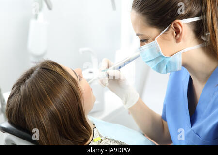 Nahaufnahme eines Zahnarztes, die Arbeit mit einem Patienten Zähne sitzen auf einem Stuhl in einer Klinik-Box mit medizinischen Geräten im Hintergrund Stockfoto