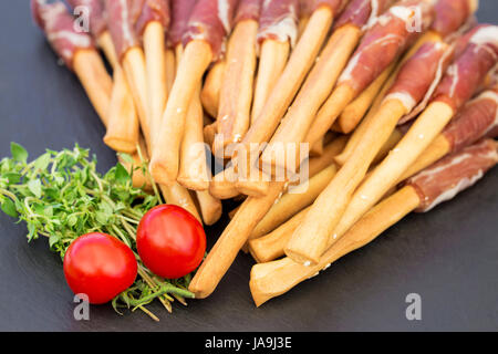 Brot klebt Grissini mit Schinken auf einer steinernen Tafel. Typische italienische Snack. Stockfoto