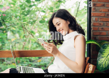 Überzeugt junge Asiatin in intelligente Freizeitkleidung mit Smartphone, tippen auf Handy. Stockfoto
