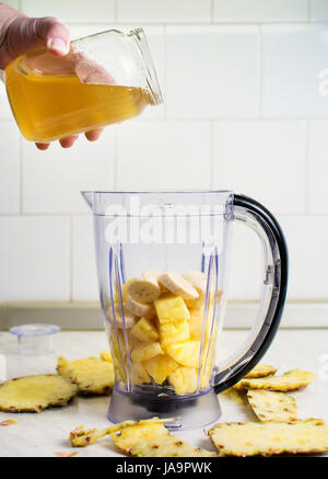 Zugabe von Honig in einem Mixer mit Obst und Wasser Stockfoto